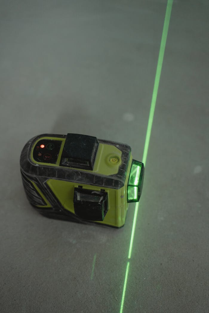 creative-01 A green laser level projecting a line on a concrete floor for alignment tasks.
