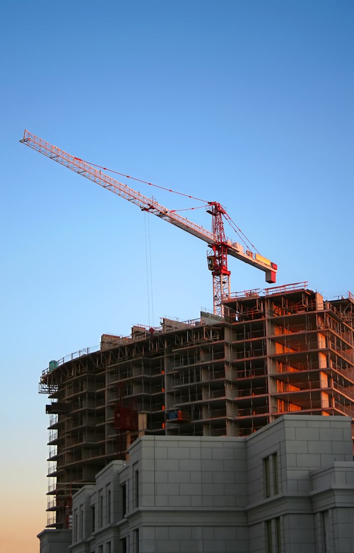 creative-03 Tower crane on a high-rise building under construction at sunset, showcasing modern urban development.